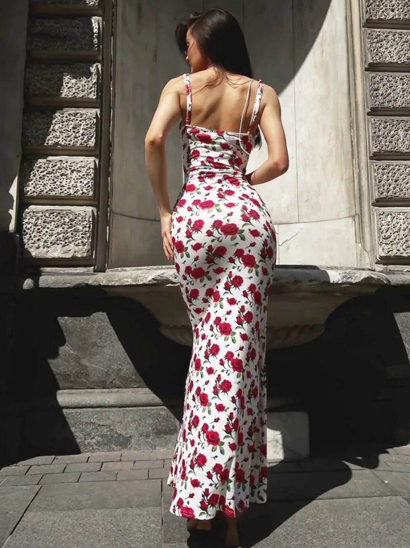 A woman models a white maxi dress with a red rose print, showing the back of the dress.