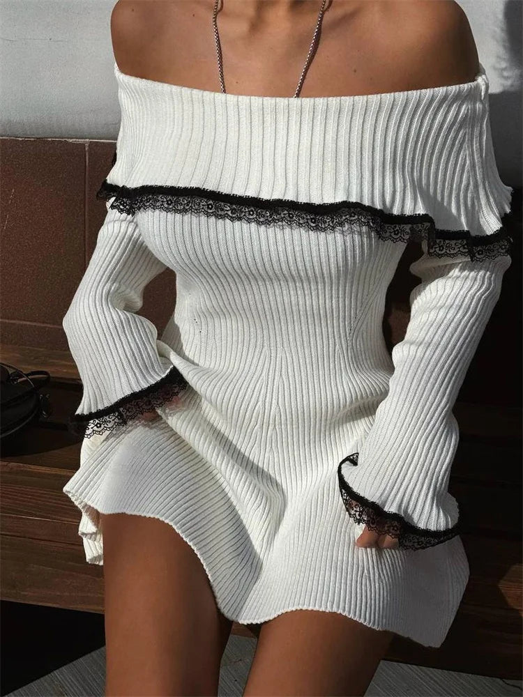 A woman wearing a white off-the-shoulder ribbed knit dress with black lace trim.