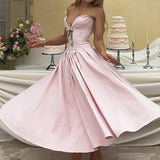 Woman in a pink satin strapless dress with a full skirt, standing in front of a cake display.
