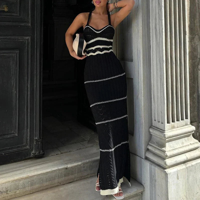 Woman wearing a black knit maxi dress with white trim and a black and white clutch