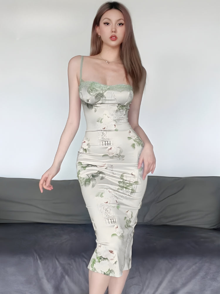Woman wearing a floral print satin slip dress with green lace trim, standing in front of a white wall and a gray sofa.