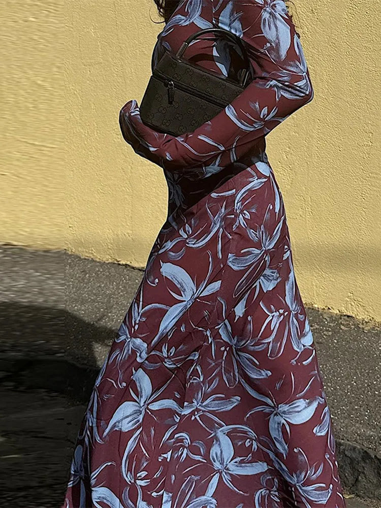 Close-up of a woman wearing a floral print maxi dress, holding a dark handbag.