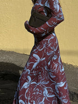 Close-up of a woman wearing a floral print maxi dress, holding a dark handbag.