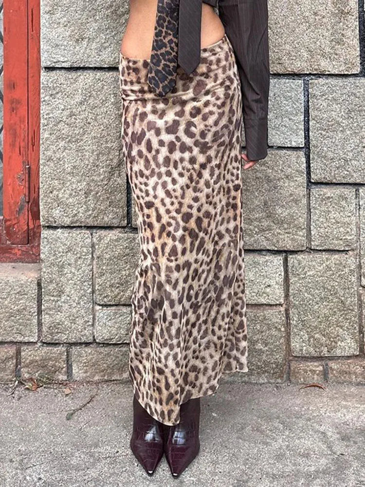 A woman wearing a long, leopard print skirt and dark boots.