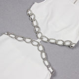 Close-up of a white dress with cut-outs and silver chain-like embellishments along the edges.