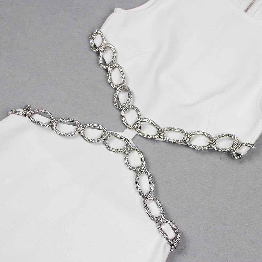 Close-up of a white dress with cut-outs and silver chain-like embellishments along the edges.