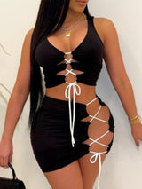 Woman wearing a black ruched lace-up crop top and mini skirt set