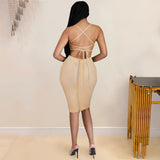 The back of a woman in a tan rhinestone-embellished dress with a strappy back and a zipper closure.