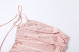 Close-up of the ruched fabric and tie detail on a pink one-shoulder dress