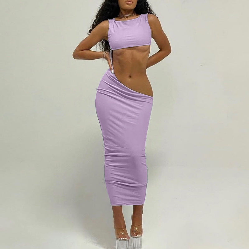 Woman in a lilac two-piece set with a cropped top and a high-waisted, ruched skirt with a side cut-out, posing against a white background.