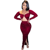 woman wearing a burgundy ruched two-piece set with a cutout top and high slit skirt
