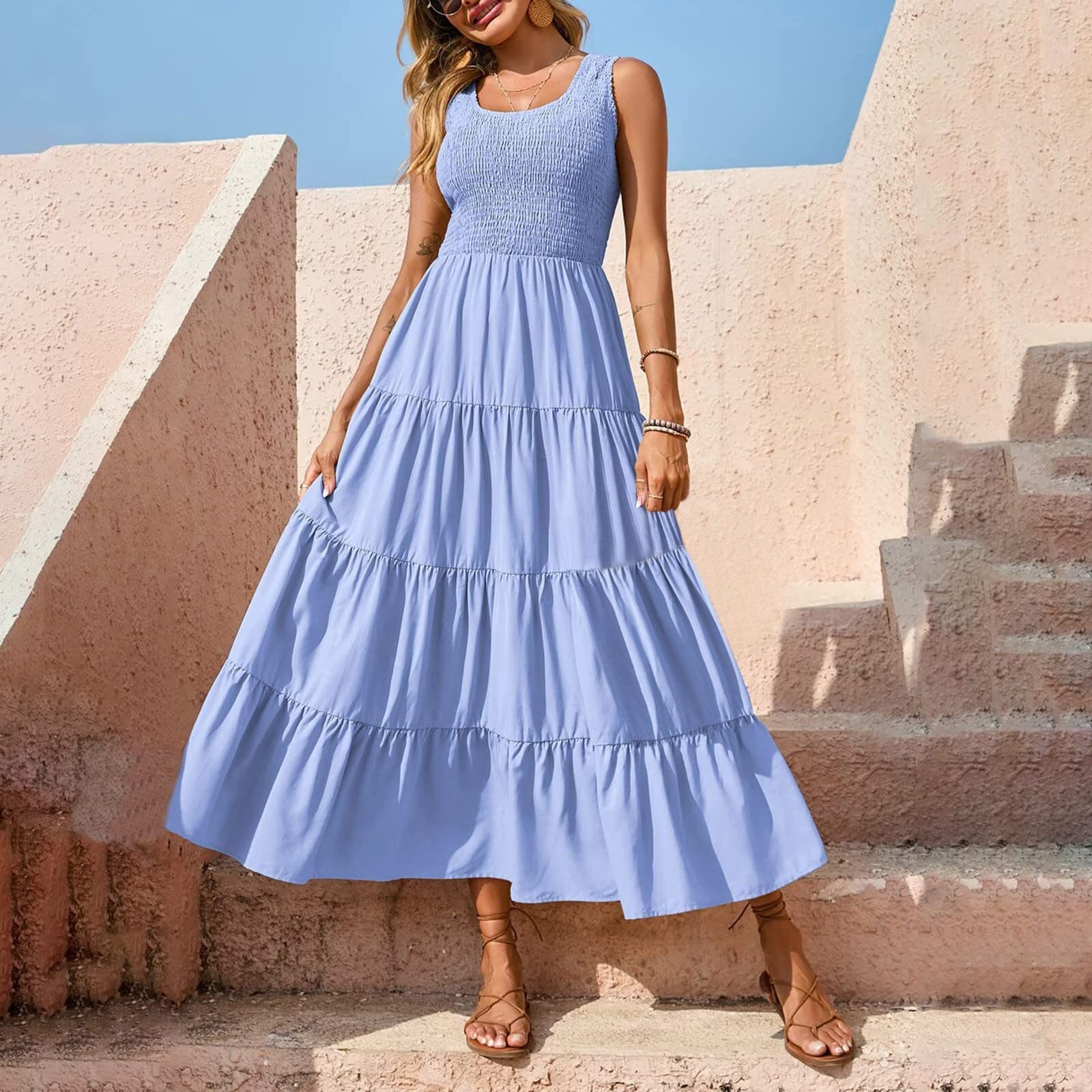 Woman wearing a blue tiered maxi dress with a smocked bodice, standing on pink stairs.