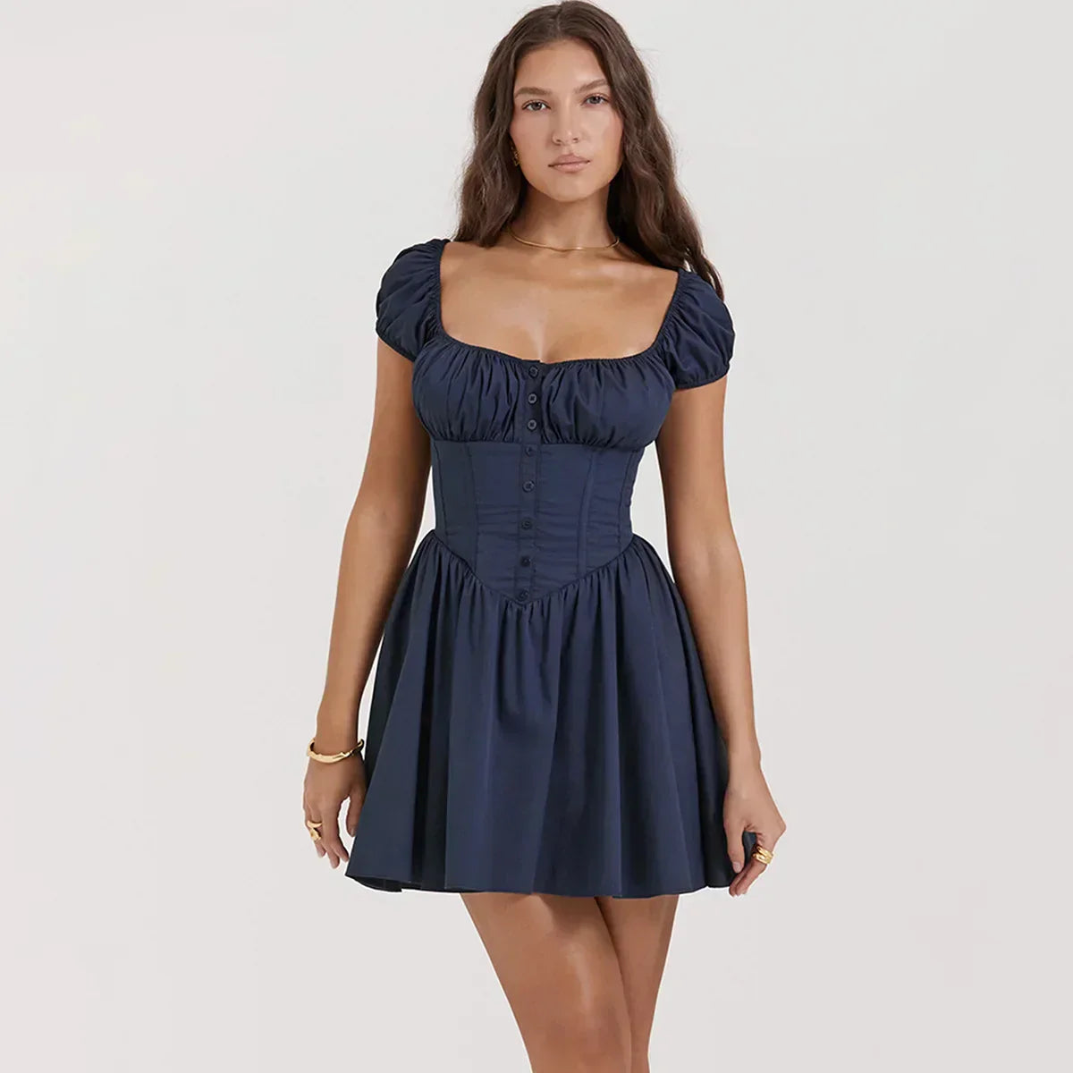 A woman wearing a navy blue short dress with puffy sleeves and a corset bodice, standing against a white background.