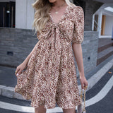 Woman wearing a floral print mini dress with a tie-front and cut-out waist