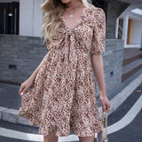 Close-up of a woman wearing a floral print mini dress with a tie-front detail