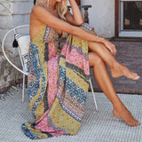 Woman sitting in a chair wearing a flowy, printed maxi dress.