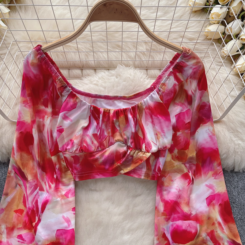 Close-up of a cropped pink, red, and white tie-dye print top with billowing sleeves.