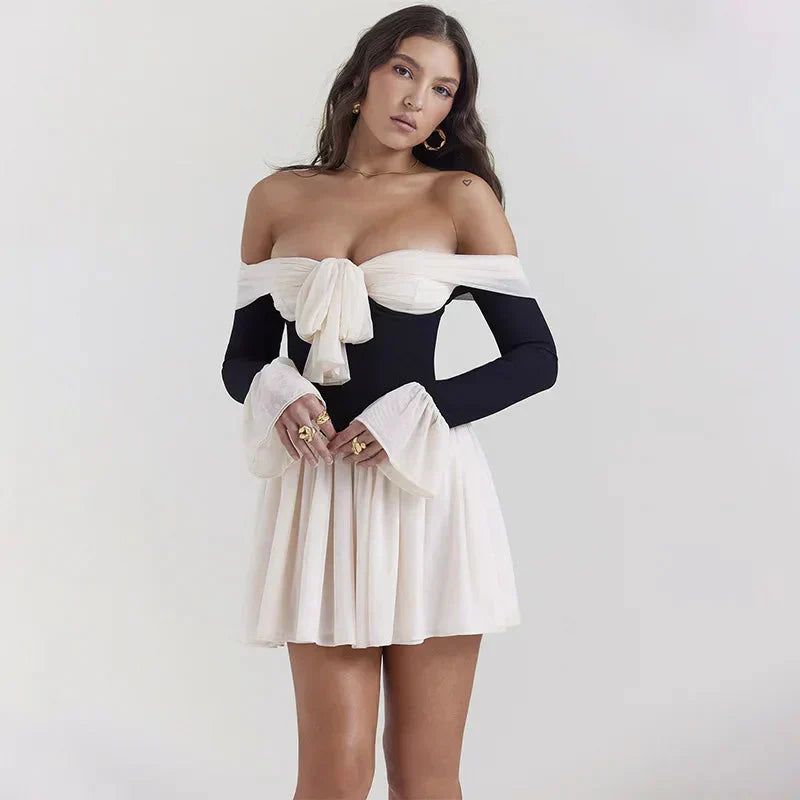 woman wearing a black and white off-the-shoulder dress with a bow detail and flared sleeves