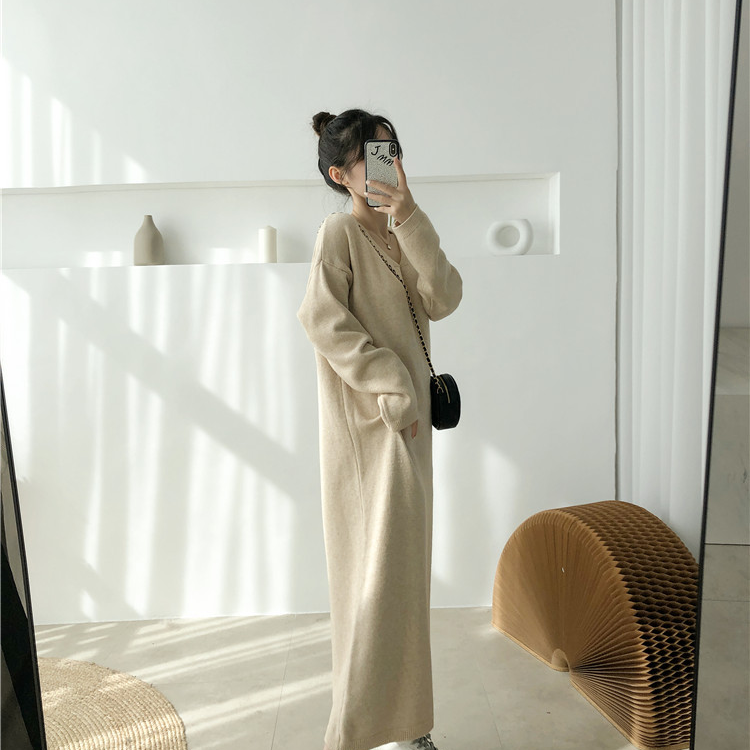 Woman wearing a long beige knit dress and a black crossbody bag