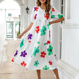 A woman wearing a white midi dress with a colorful floral print and puff sleeves.