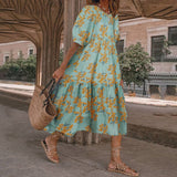 A woman wearing a light blue midi dress with a yellow floral print and puff sleeves, carrying a straw bag.