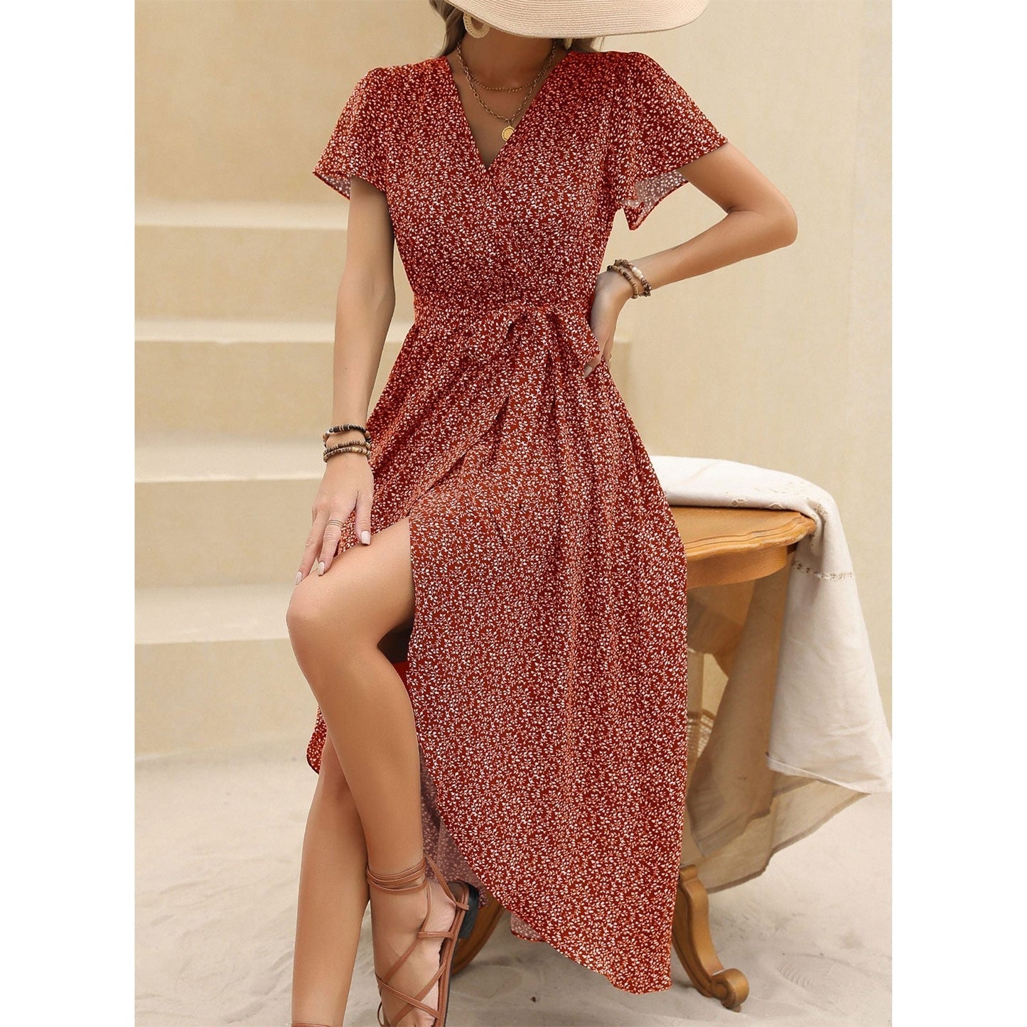 woman in red floral print wrap dress sitting on a stool