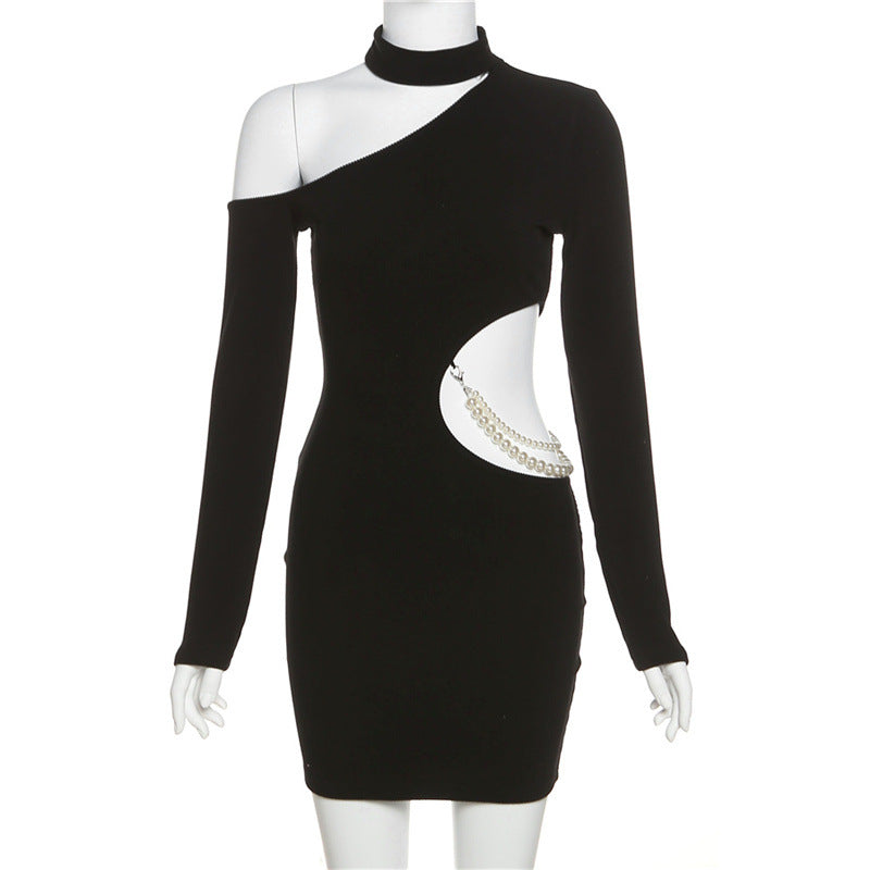 A black mini dress with an asymmetrical neckline, long sleeves, and a cut-out with pearl embellishment displayed on a mannequin.