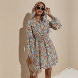 A woman poses confidently in a yellow floral print dress with bishop sleeves and a v-neck.