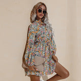 A woman holds a clutch bag while wearing a yellow floral print dress with long sleeves.