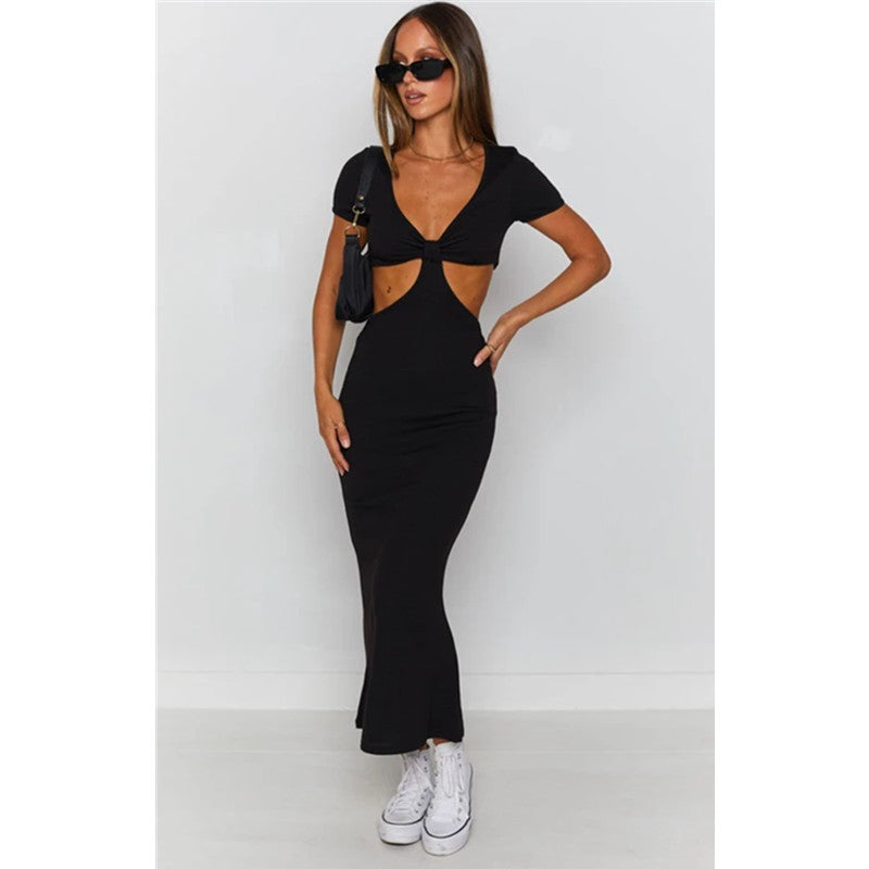 Woman wearing a black cut-out midi dress with short sleeves, sunglasses, and white sneakers.