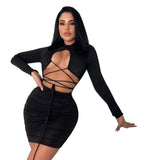 Woman in a black long-sleeved, cut-out, lace-up, ruched mini dress against a white background.