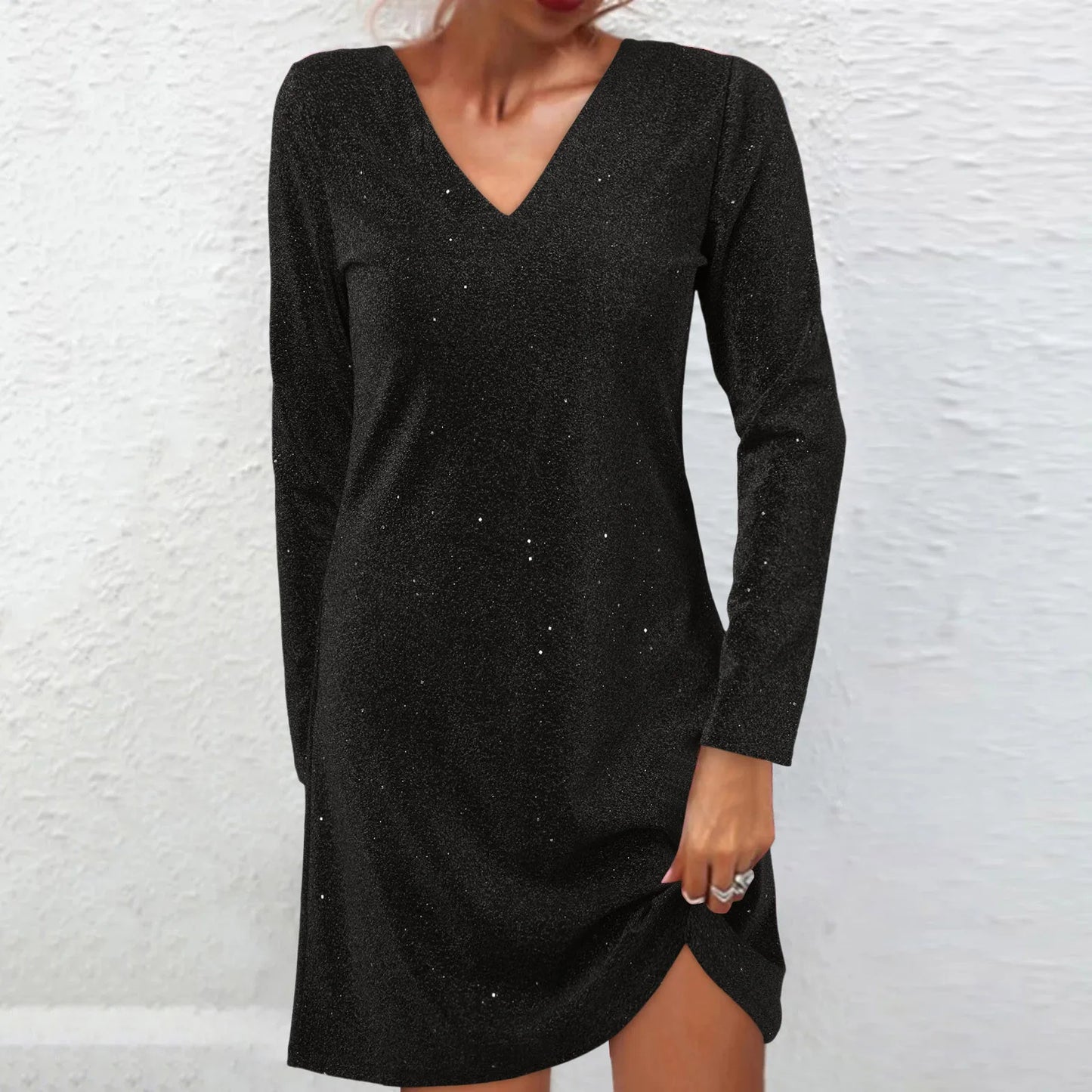 Woman wearing a black sparkly long-sleeve v-neck dress with a slit.