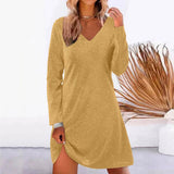 Woman wearing a gold sparkly long-sleeve v-neck dress with a slit.