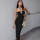 Woman in a black cutout halter neck dress holding a clutch