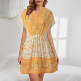 woman wearing a yellow and white floral print short sleeve dress with a v-neck and empire waist
