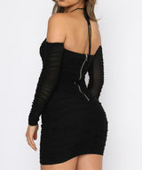 A back view of a woman wearing a black ruched bodycon dress with off-the-shoulder long sleeves and a halter neckline, featuring a zipper closure.