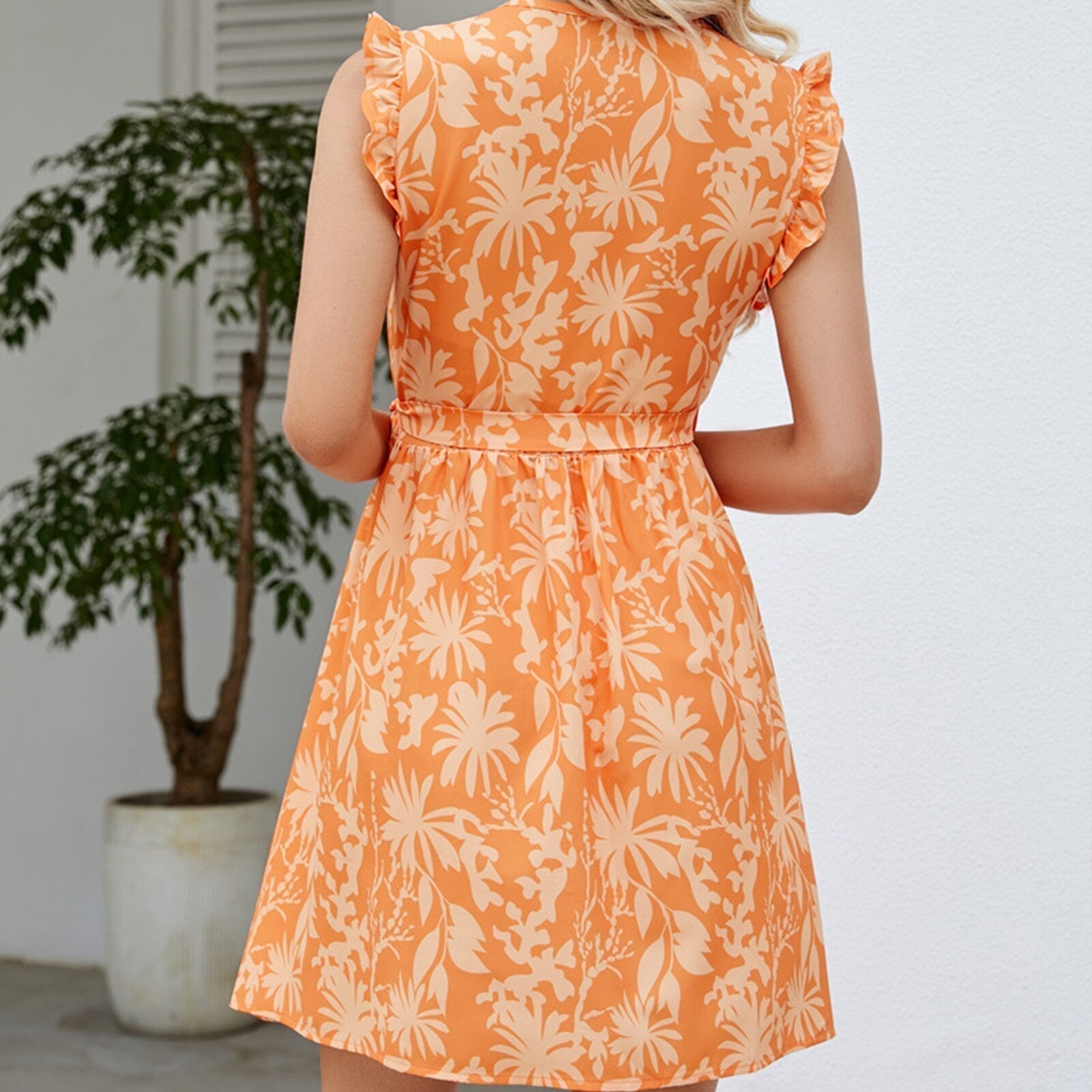 Back view of a woman in an orange floral print wrap dress