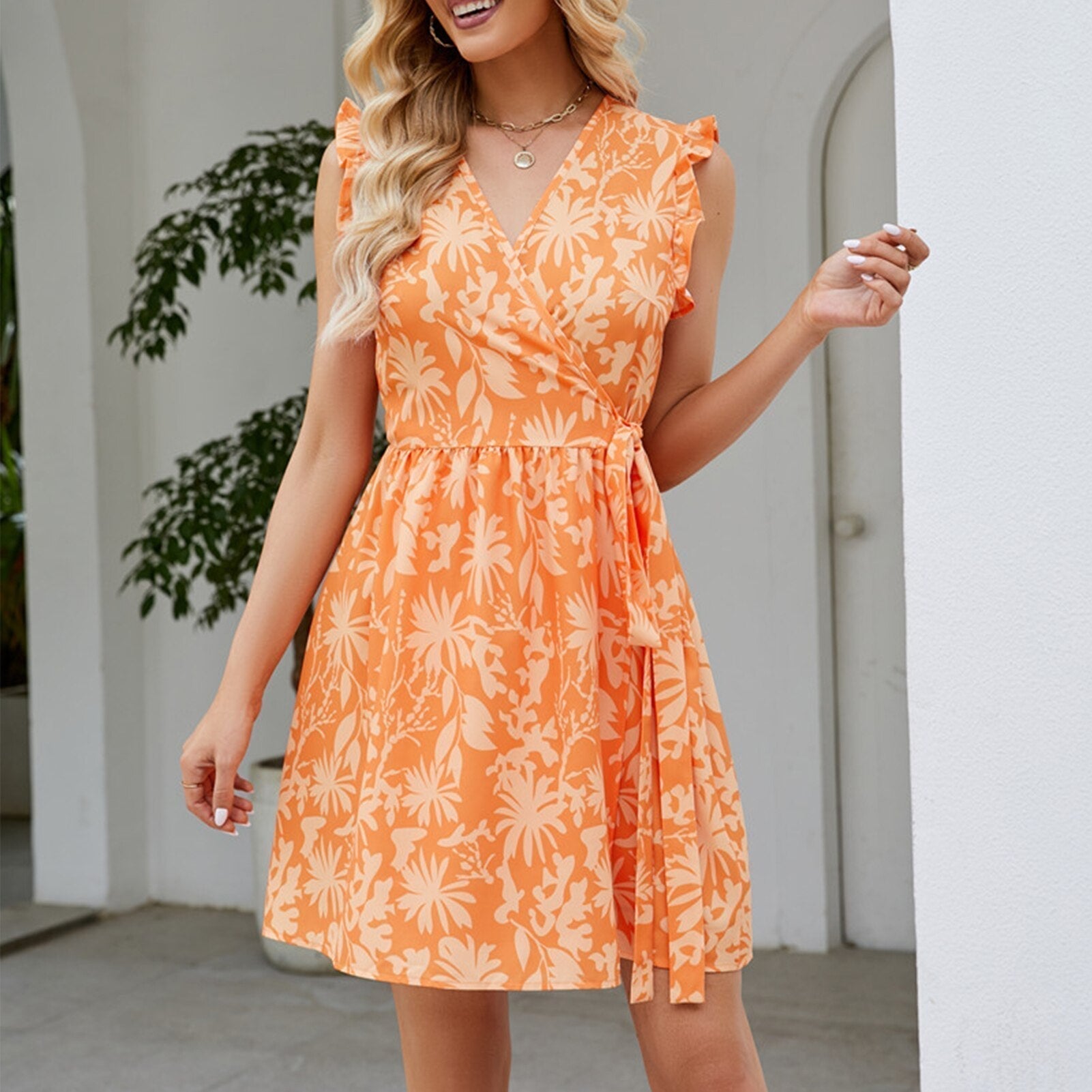 Woman in an orange floral print wrap dress smiling