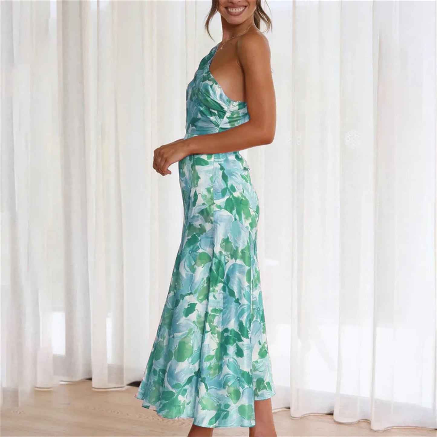 Woman wearing a green and blue floral one-shoulder midi dress from the side