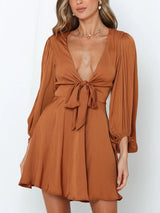 woman wearing a brown satin mini dress with a tie-front detail and puffed sleeves