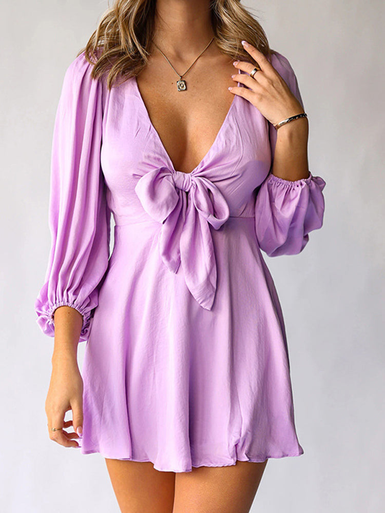 woman wearing a purple satin mini dress with a tie-front detail and puffed sleeves