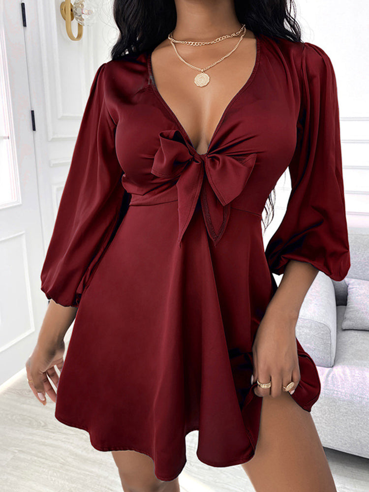 woman wearing a burgundy satin mini dress with a tie-front detail and puffed sleeves