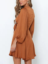 back view of a woman wearing a brown satin mini dress with a tie-front detail and puffed sleeves