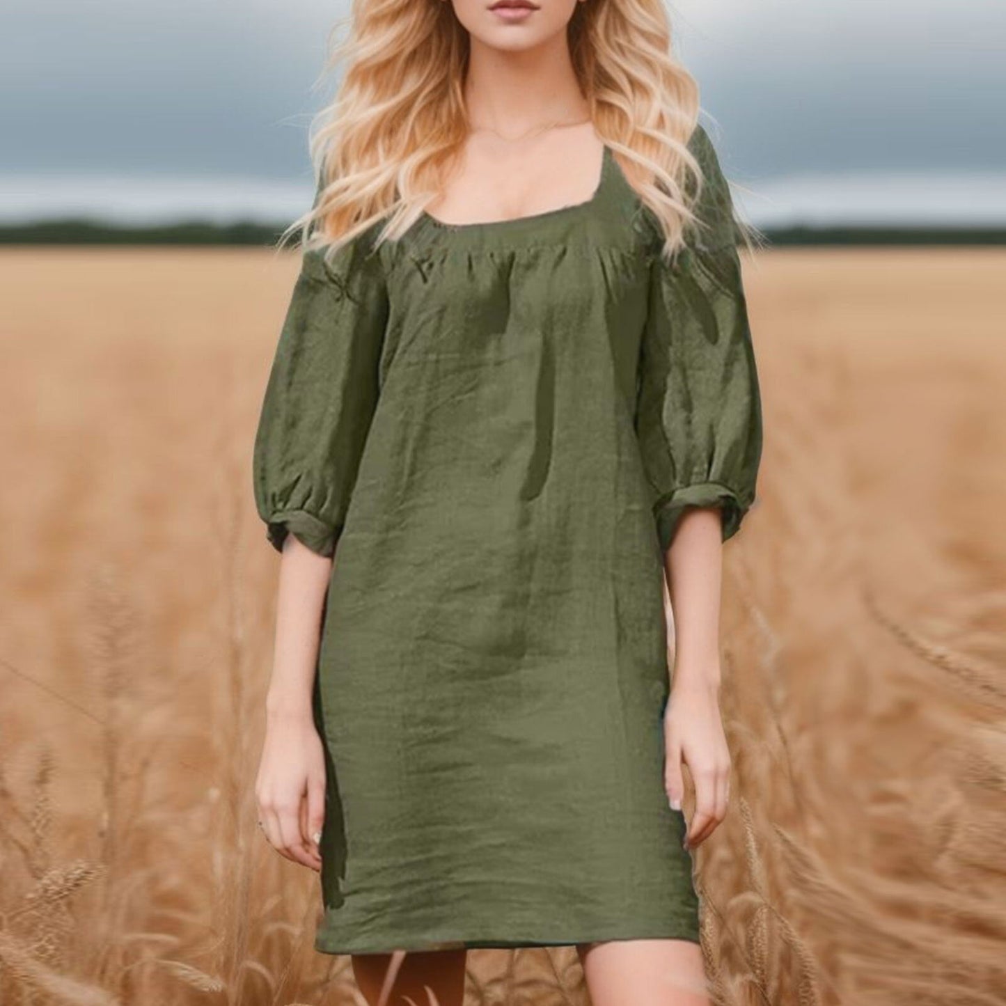 woman in a green linen mini dress with puff sleeves standing in a wheat field