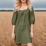 woman in a green linen mini dress with puff sleeves standing in a wheat field
