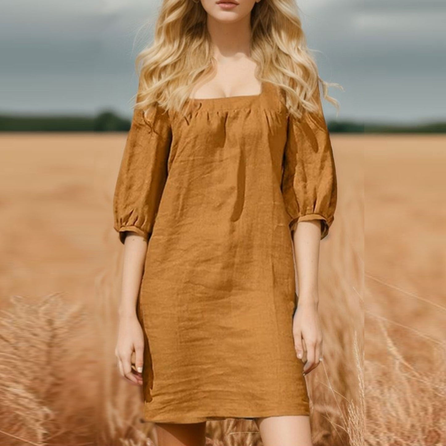 woman in a mustard yellow linen mini dress with puff sleeves standing in a wheat field
