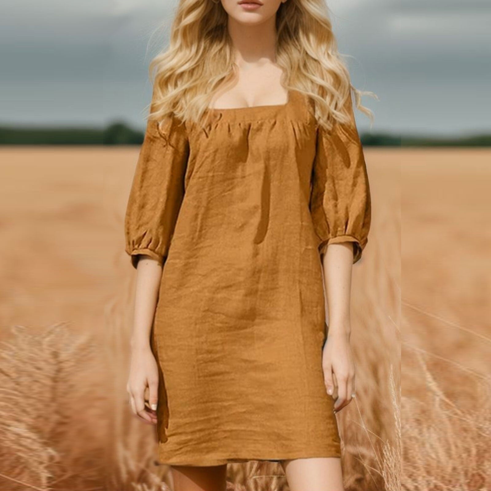 woman in a brown linen mini dress with puff sleeves standing in a wheat field
