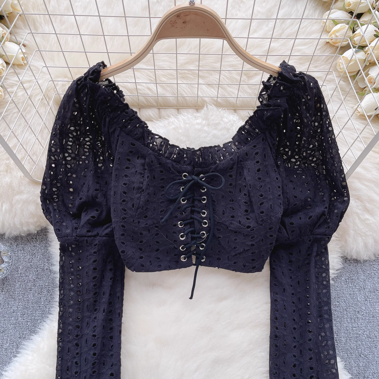 Close-up of the black eyelet lace crop top's lace-up front and ruffled neckline.