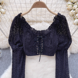 Close-up of the black eyelet lace crop top's lace-up front and ruffled neckline.