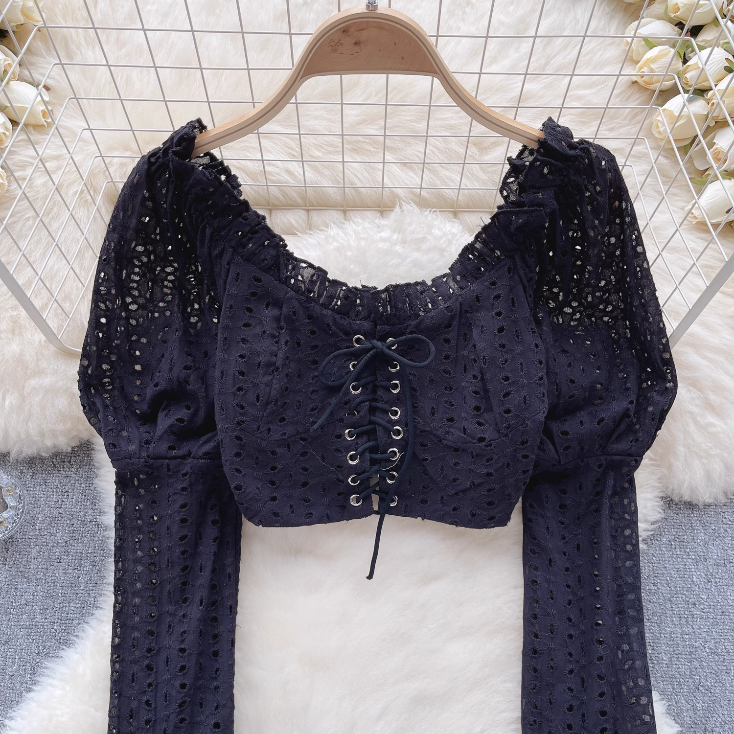 Close-up of the black eyelet lace crop top's lace-up front and ruffled neckline.